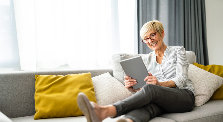 Photo of a woman on a couch looking at a tablet computer