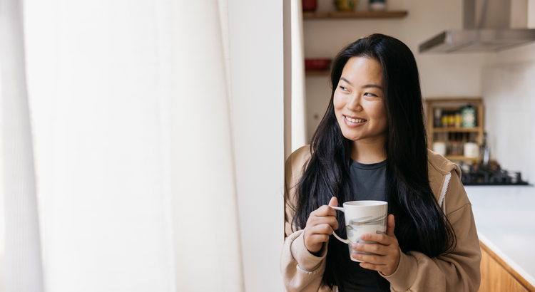 Photo of a smiling woman holding a mug of coffee