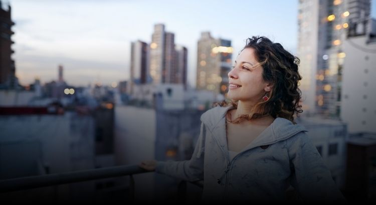 Photo of woman on rooftop looking over a city