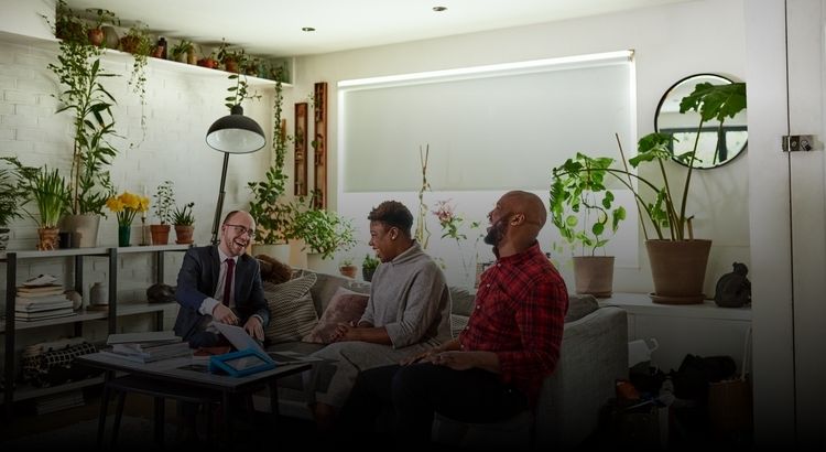Couple in a living room laughing with a third person