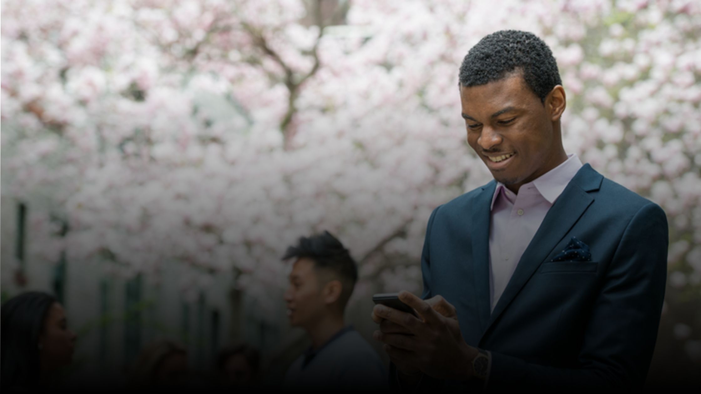 Photo of a man outside smiling while using his cell phone