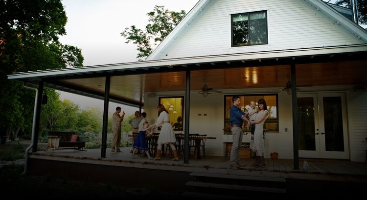 Photo of several generations of people on the front porch of a house