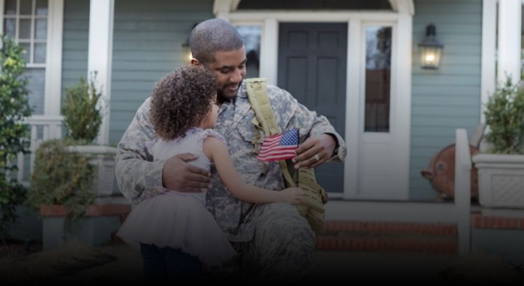 Photo of a military veteran hugging their child in front of a home