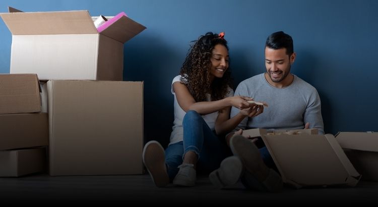 Couple sitting on the floor with moving boxes