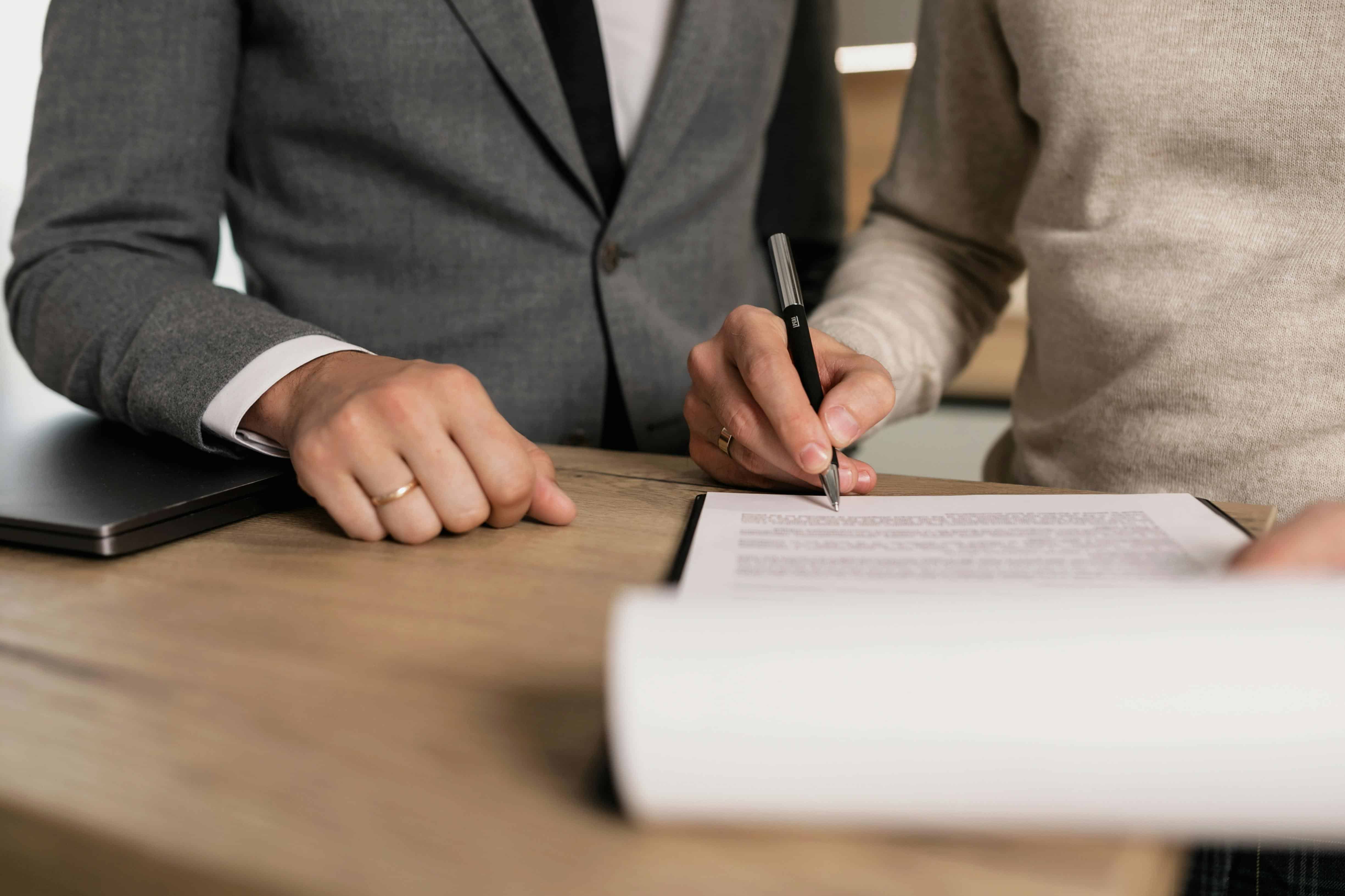 Woman signing a document given to her by a man in a suit