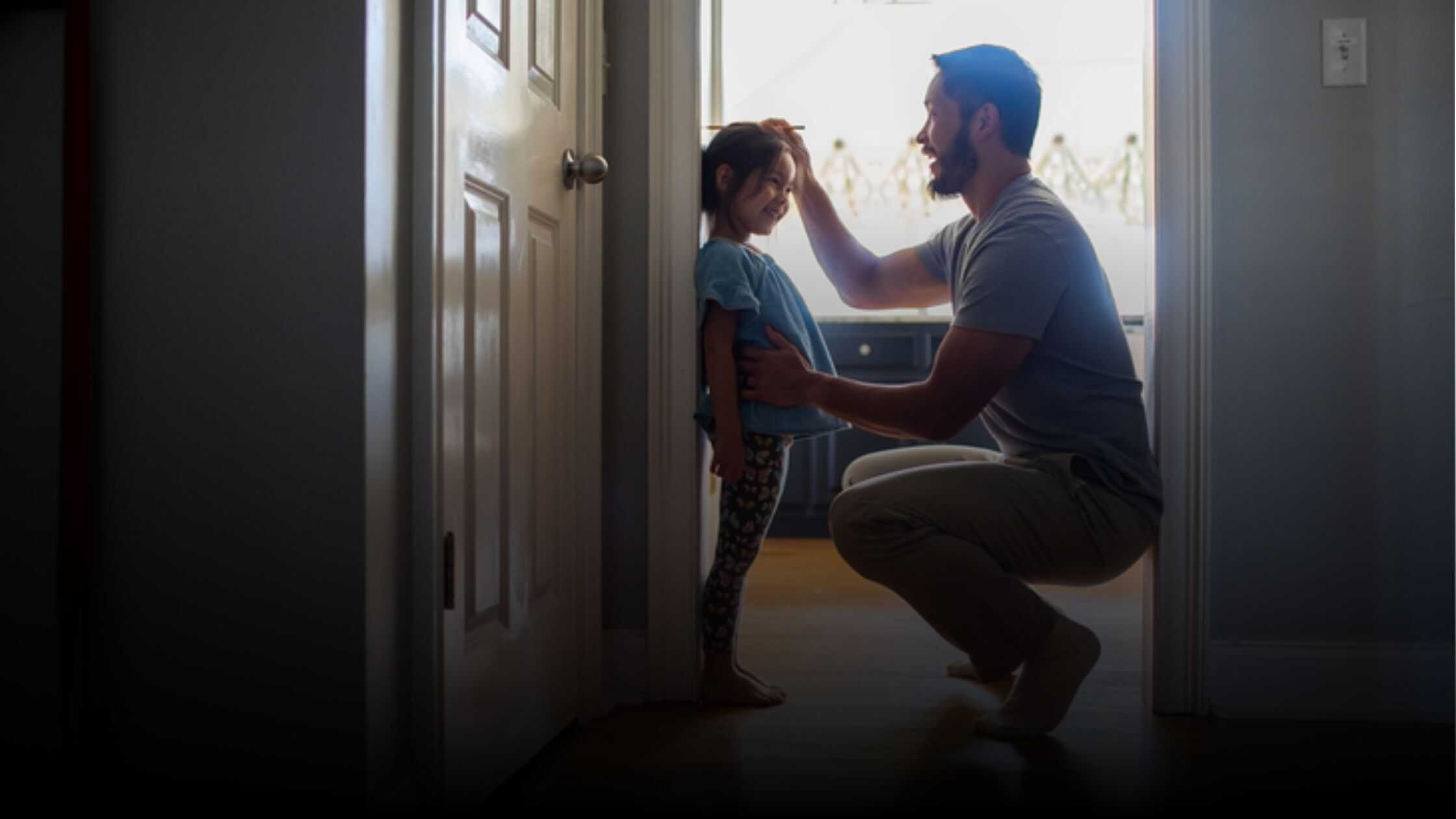 Man measuring his child against a doorjamb