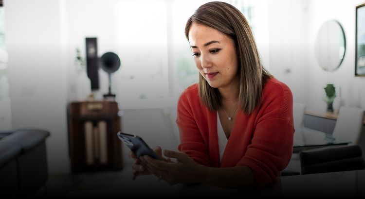 Woman sitting at a desk looking at her cellphone