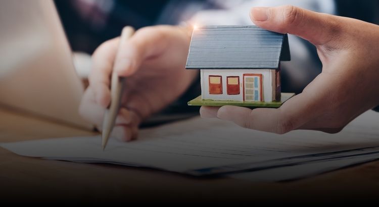 Close up of person holding a toy house and looking over a contract