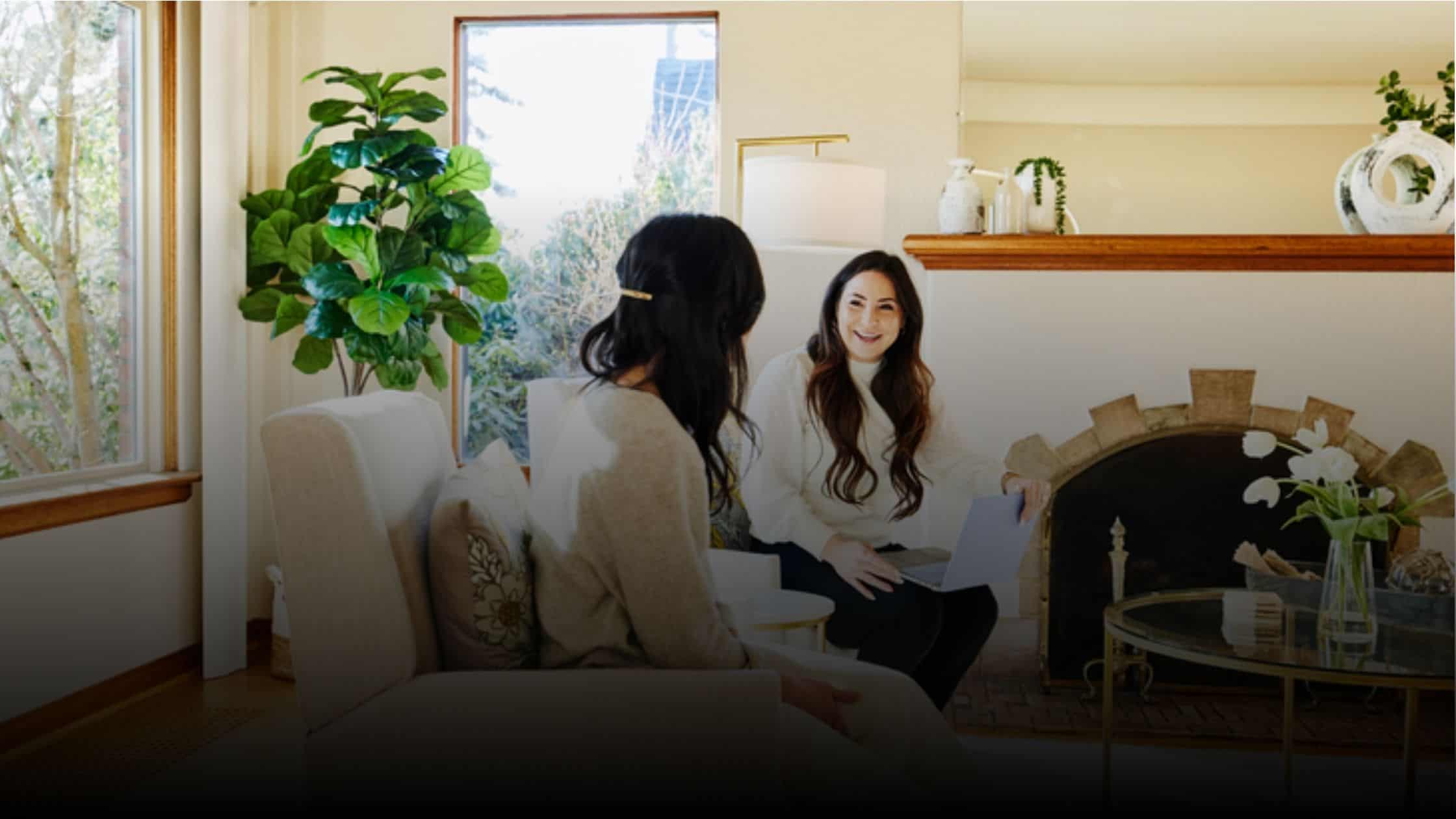 Two women sitting on a couch discussing something