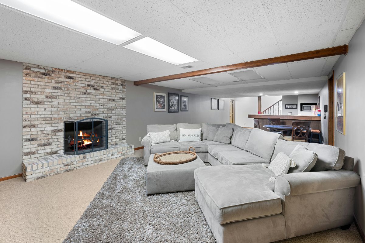 Finished basement with a sectional sofa, brick fireplace, and built-in bar in a Kane or DuPage County home