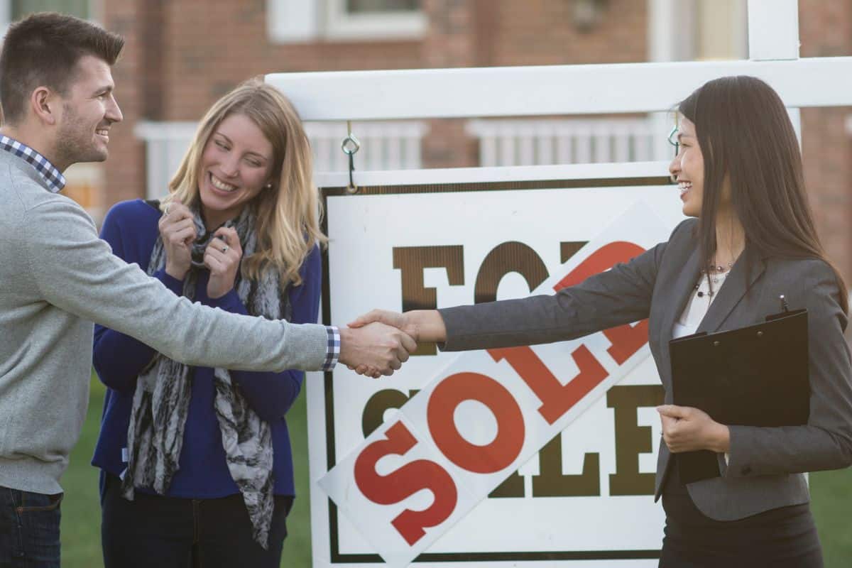 Happy homebuyers shaking hands with a Realtor after purchasing a home in Kane County Illinois