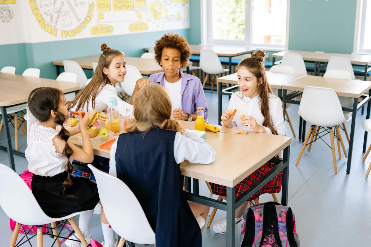 Students eating lunch together in a bright school cafeteria, representing how school districts can influence home values