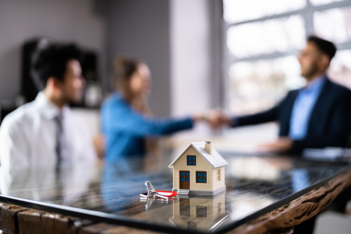 Home buyers meeting with real estate agent in Illinois with house model and keys on table during closing consultation