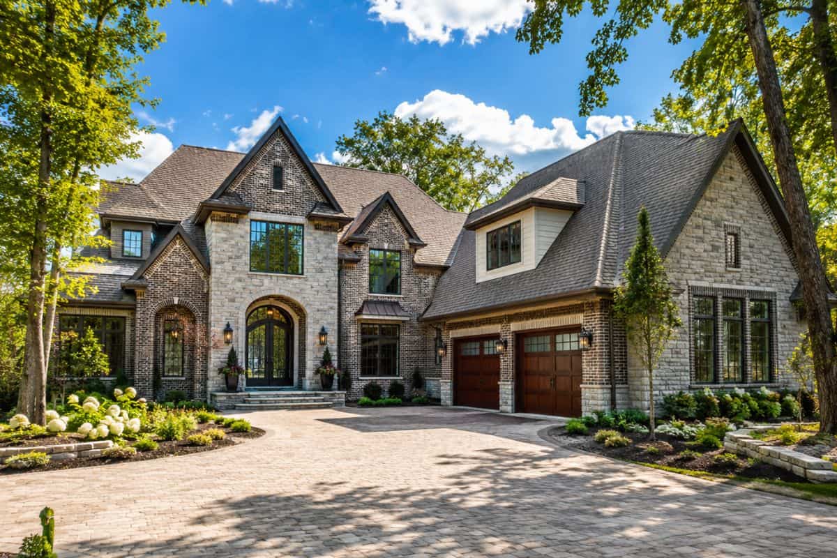 Luxury estate home in Naperville IL with stone exterior, paver driveway and mature trees