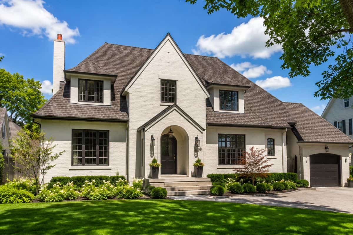White brick luxury home in Naperville IL with manicured landscaping and mature trees.