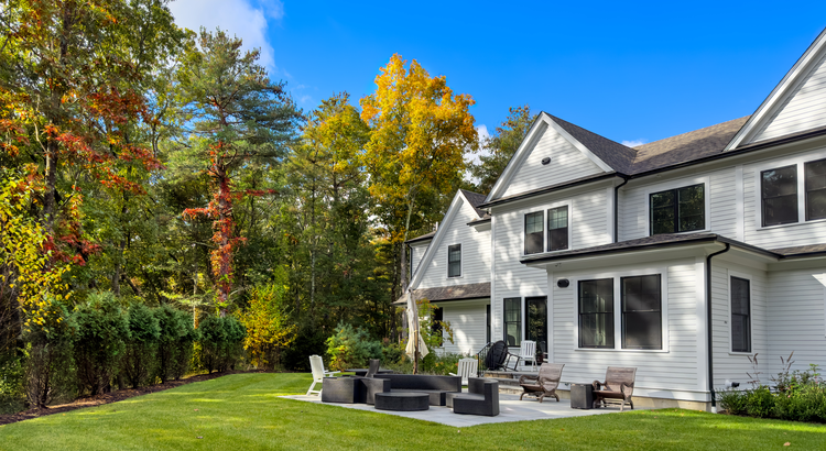 Modern white home with landscaped backyard and colorful fall trees